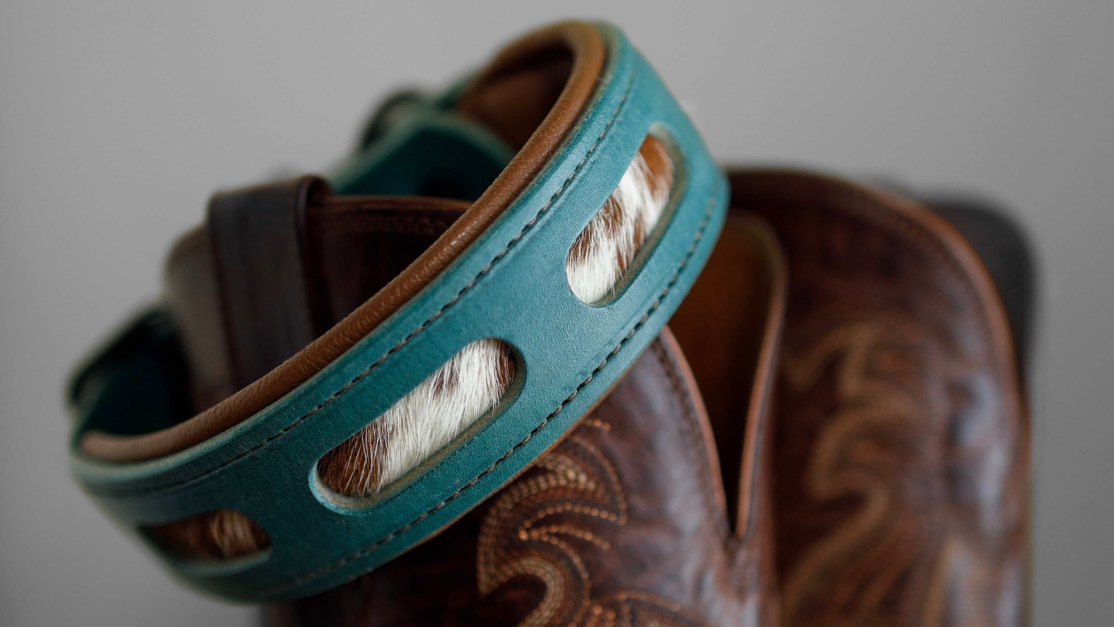 Handcrafted leather collar with inlays, featuring hair on hide.